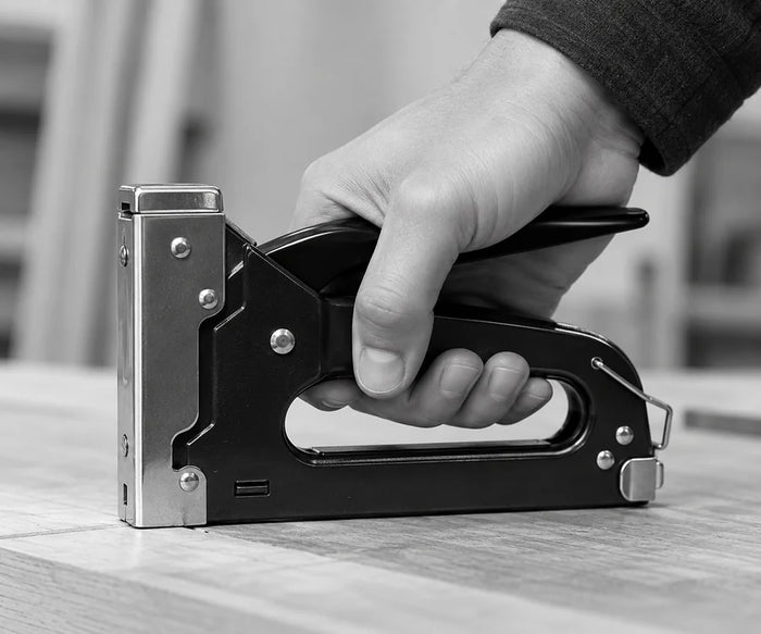Normal gun tacker being squeezed by hand, black and white